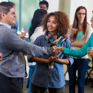 A woman with medium length curly hair wearing a jean shirt and blue scarf talking to parents about how to support their neurodiverse children.