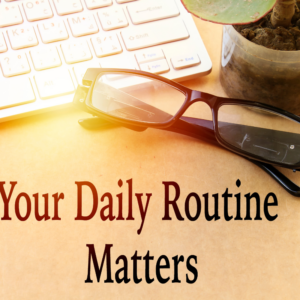 Images of computer keyboard and glasses on a wood table. With the words Your Daily Routine Matters in black font