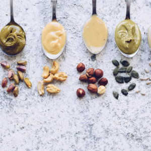 Nutritious Lunch with 4 spoons filled with nut butters and matching nuts in front of them.