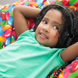 clack child wearing headphones with headphones on laying on a bean bag Creating a sensory-friendly holiday