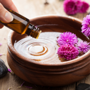 wooden bowel with pink floating flowers with water in it, a hand dropping in essential oils Creating a sensory-friendly holiday